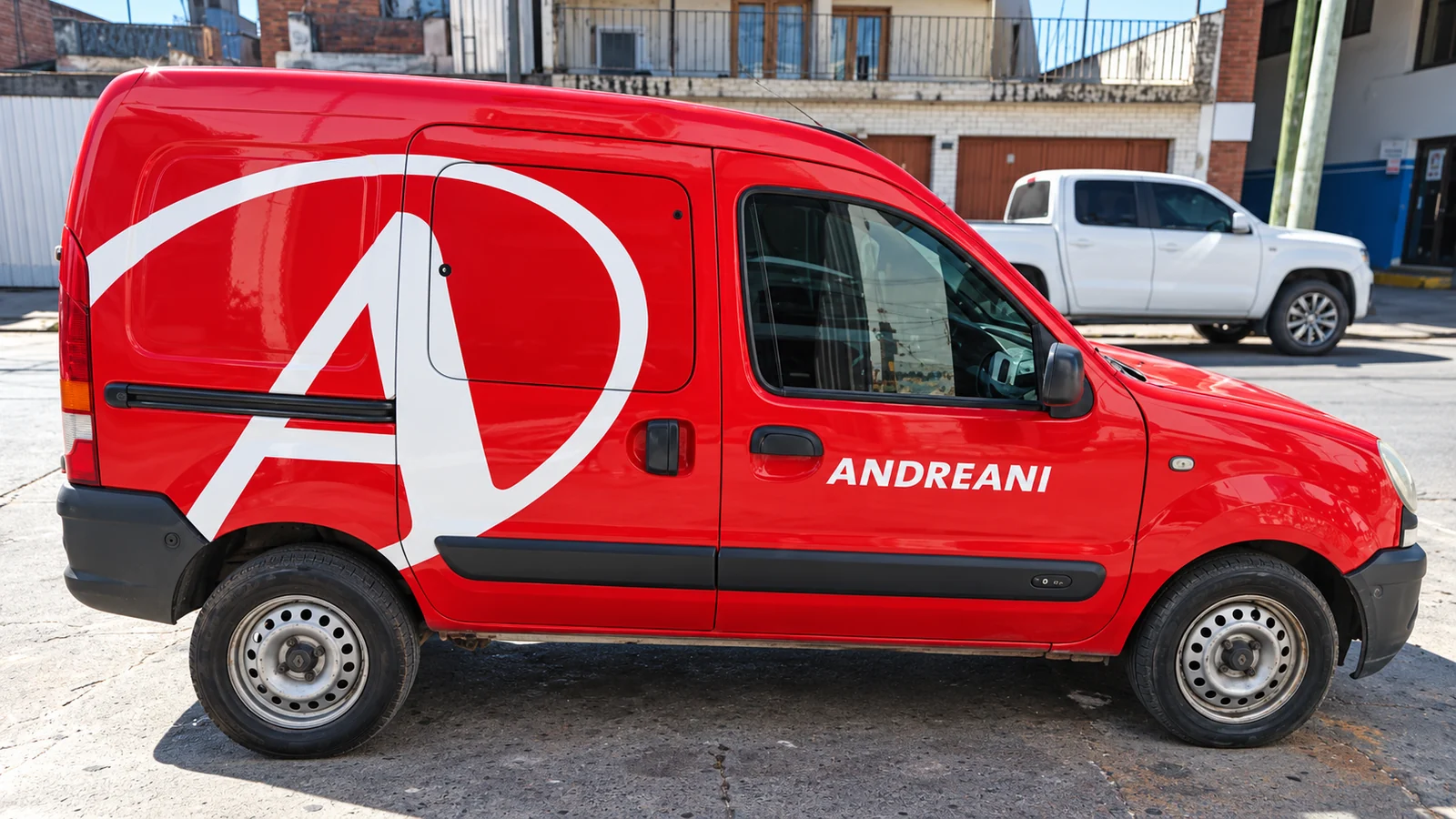 Camioneta roja de Andreani con ploteo blanco en el lateral.
