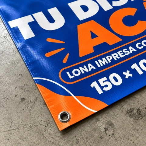 Detalle de una lona impresa azul y naranja con ojal metálico y borde reforzado